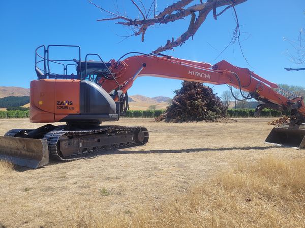 14-tonne Hitachi ZAXIS 135US excavator stacking burn piles on vineyard property