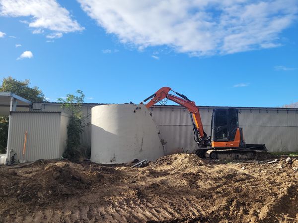 14-tonne excavator with breaker attachment demolishing concrete tank, Brancott Estate