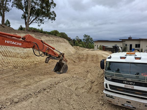 Excavator grading earth on cut and fill building platform