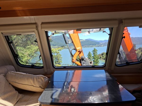View from inside the caravan: the digger boom framed in the window with the Sound beyond