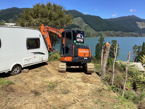 Caravan parked on its new spot above Mahau Sound with the DirtPro Hitachi beside it