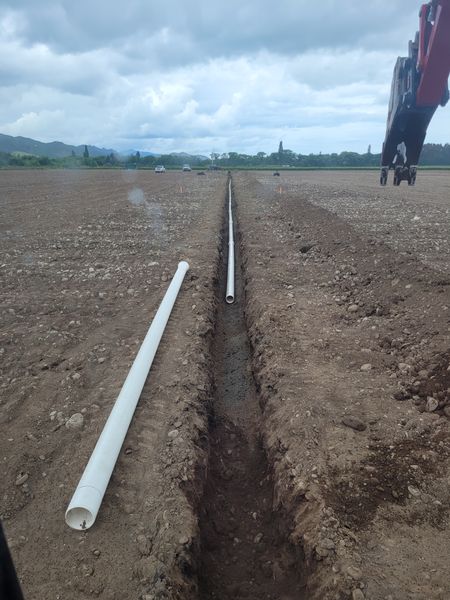 PVC drainage pipe being laid in excavated trench